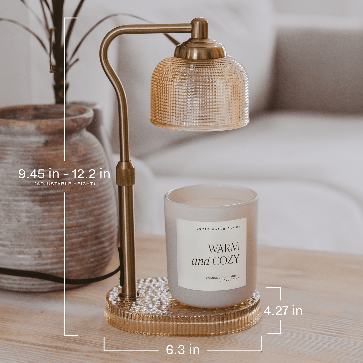 Glass candle lamp warmer with a neutral glass shade, gold adjustable arm, and elegant flameless design.