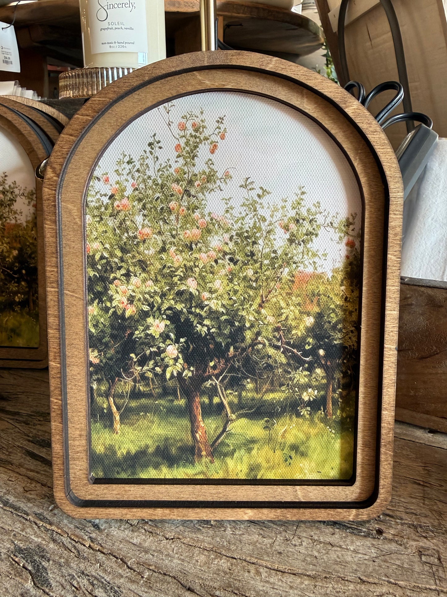Arch Top Apple Orchard Framed Canvas Art featuring a peaceful orchard landscape in a handcrafted arched wood frame with an Early American finish.