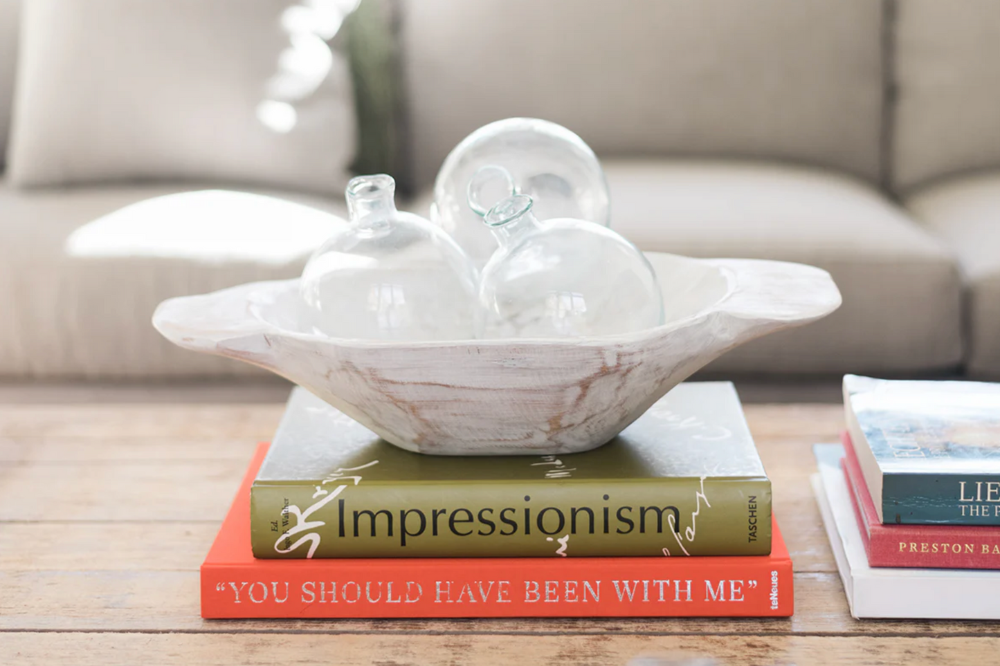 Handcrafted glass sphere bud vase with organic shape styled on a coffee table