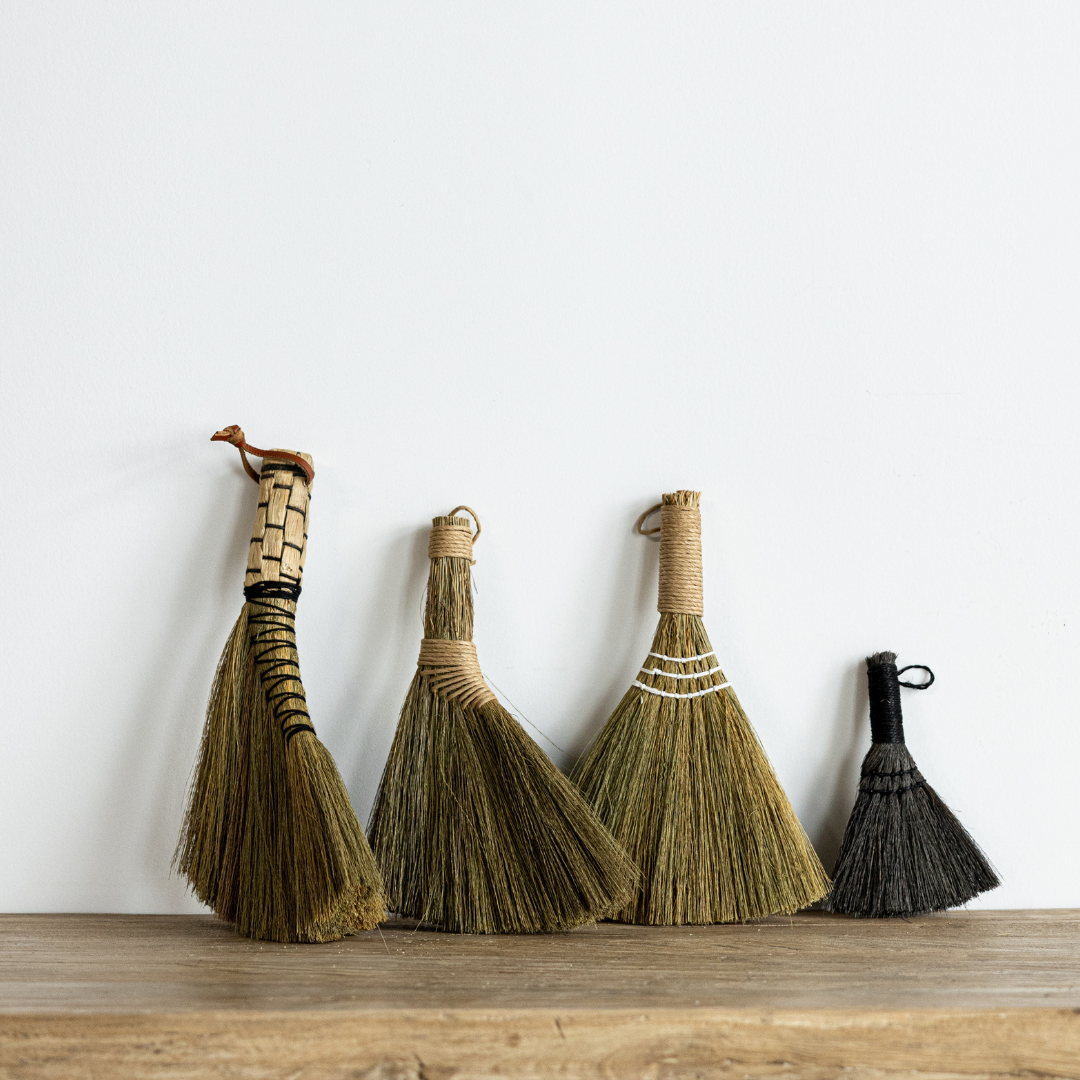 Handwoven seagrass handle broom styled as a decorative accent in an entryway or kitchen