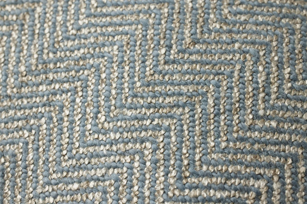 Close-up of the blue hand-stitched pillow highlighting the textured stitching, contrast flange, and hidden zipper with antique bronze Loloi logo pull.