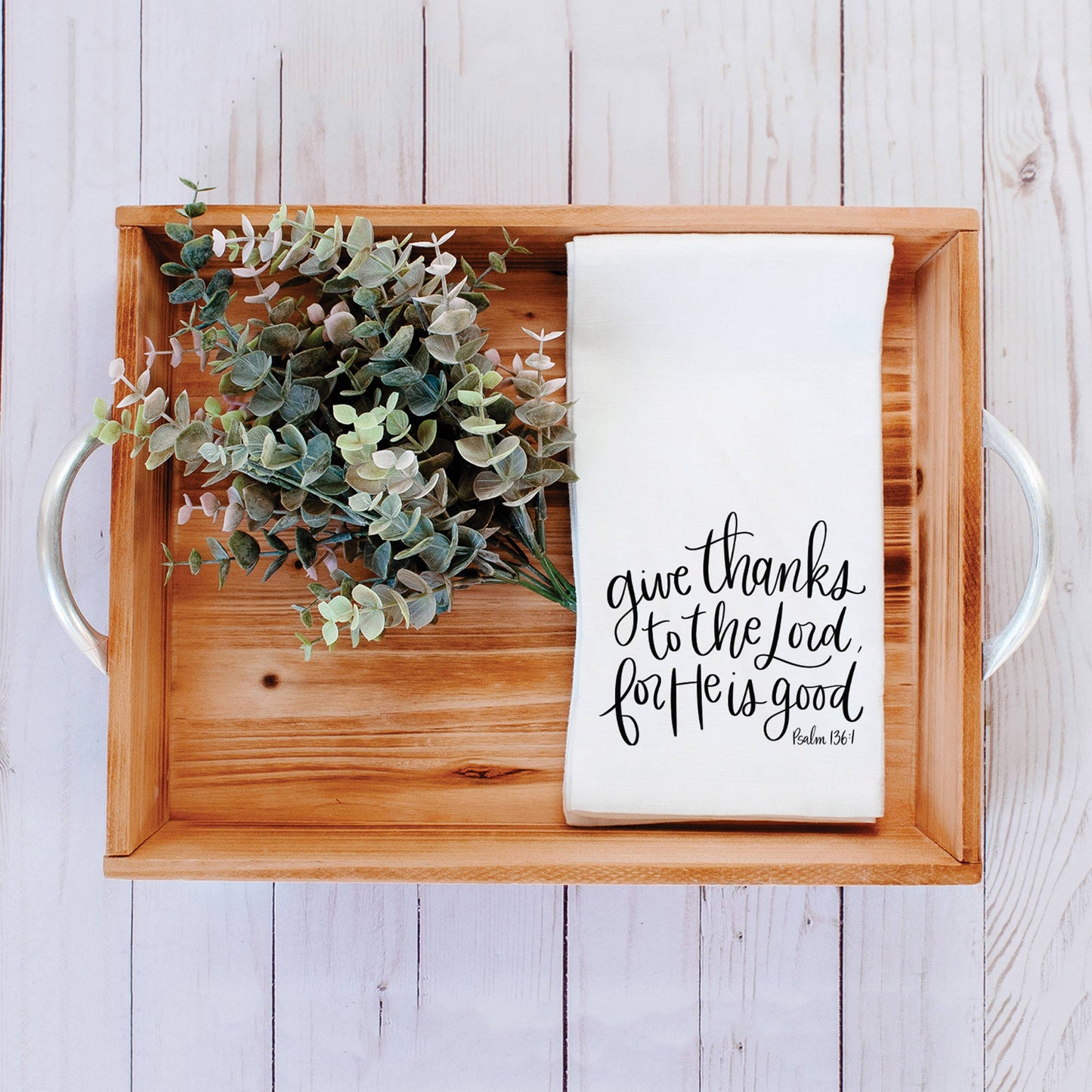 Give Thanks to the Lord tea towel styled beside a wooden bread board and fresh eucalyptus, creating a welcoming, faith-filled kitchen vignette.