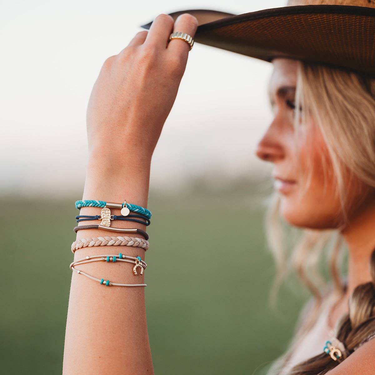Stride turquoise and gold cowboy hair tie bracelets worn as a stacked Western-inspired bracelet set.