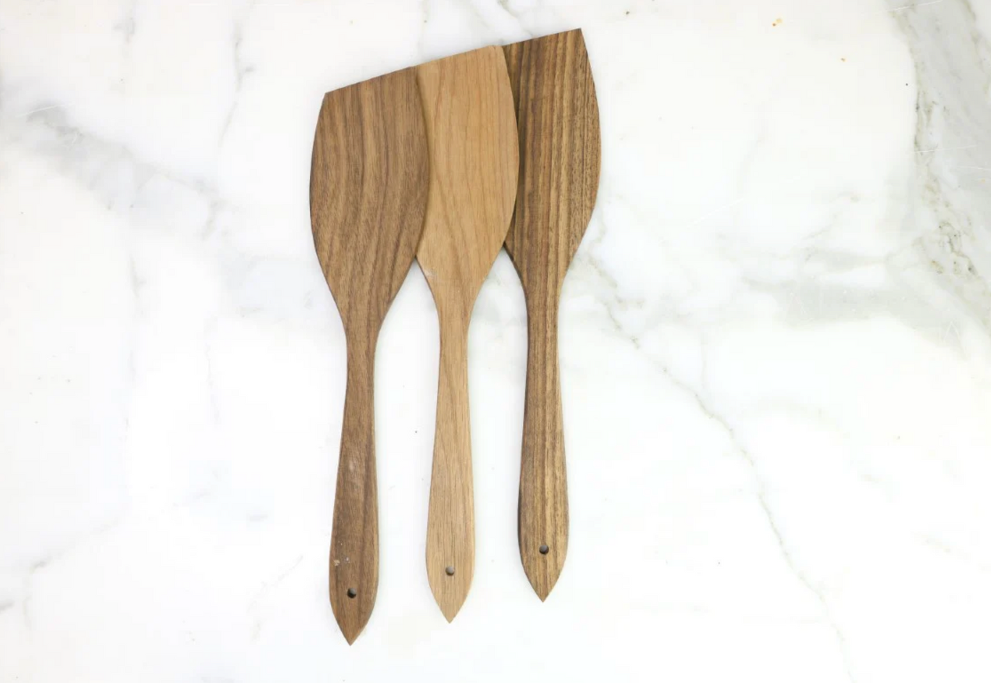Three wooden spatulas on a white marble surface