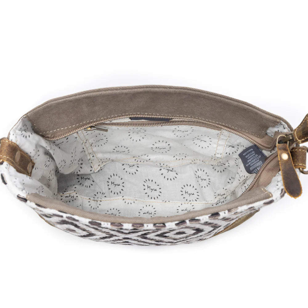 Close-up of a brown leather bag with patterned interior on a white background