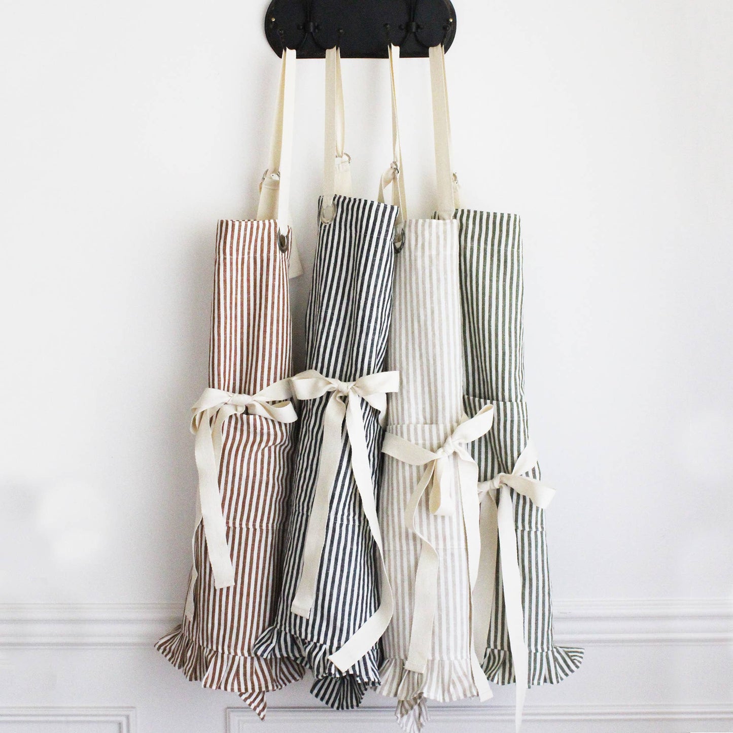 Green Pinstripe Ruffle Apron made from a premium cotton and linen blend with charming ruffle trim, an adjustable neck strap, and a front pocket.