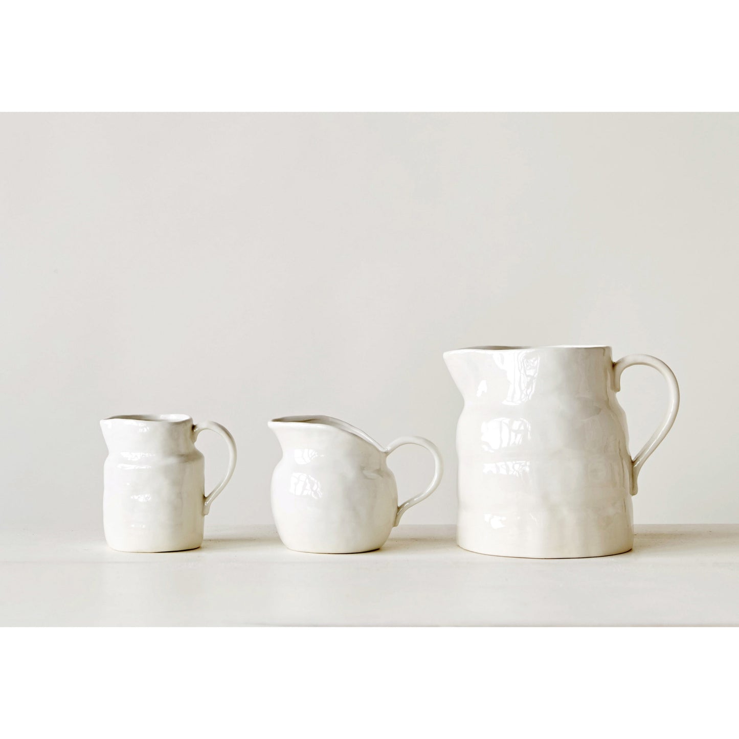 Small stoneware pitcher serving cream and juice on a thoughtfully styled breakfast table.
