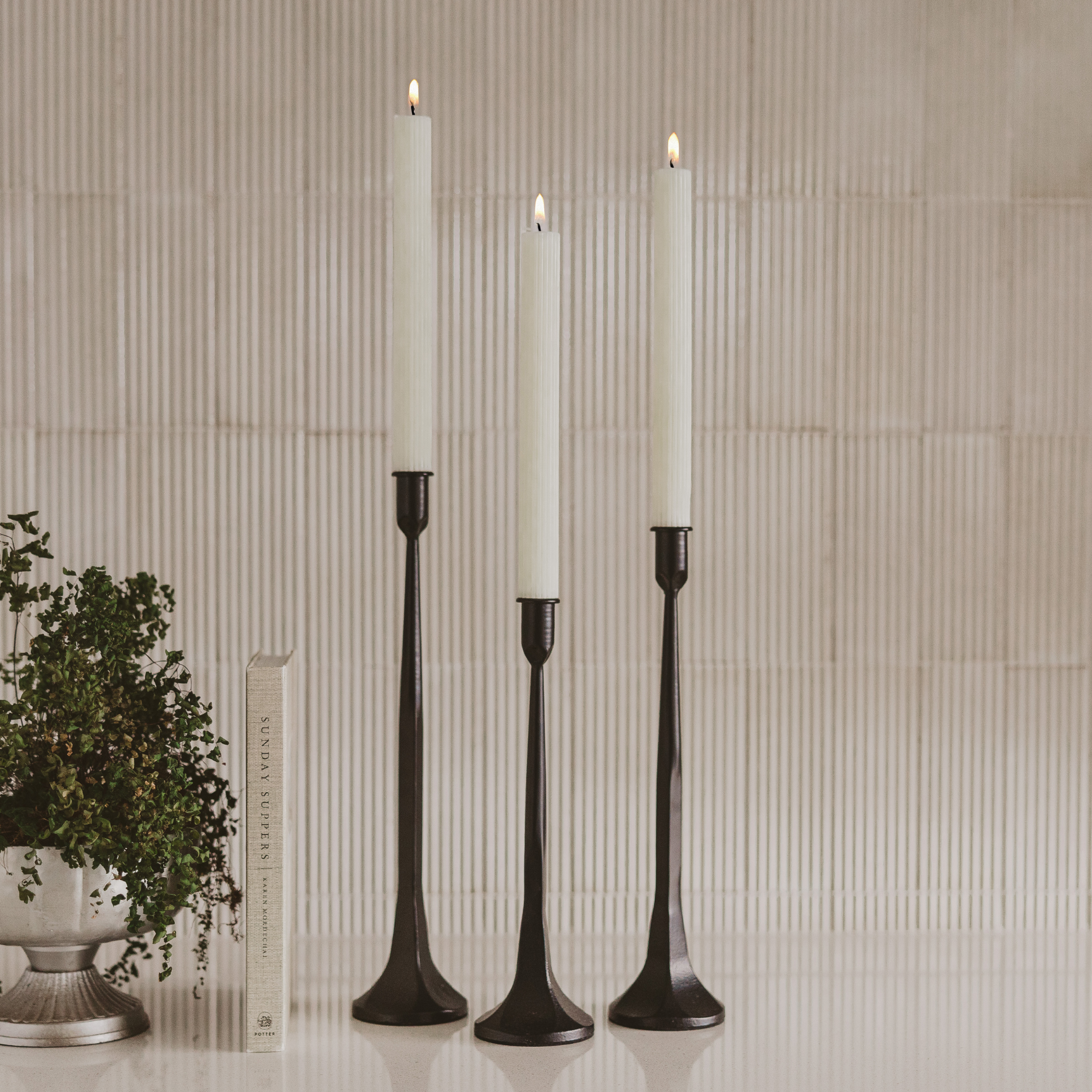 White fluted taper candles displayed in candle holders on a beautifully styled.