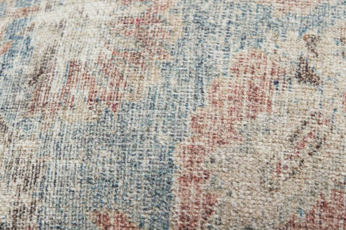 Close-up of the Pacifica pillow highlighting the woven texture, soft sky blue tones, knife-edge finish, and hidden zipper with antique bronze Loloi logo pull.