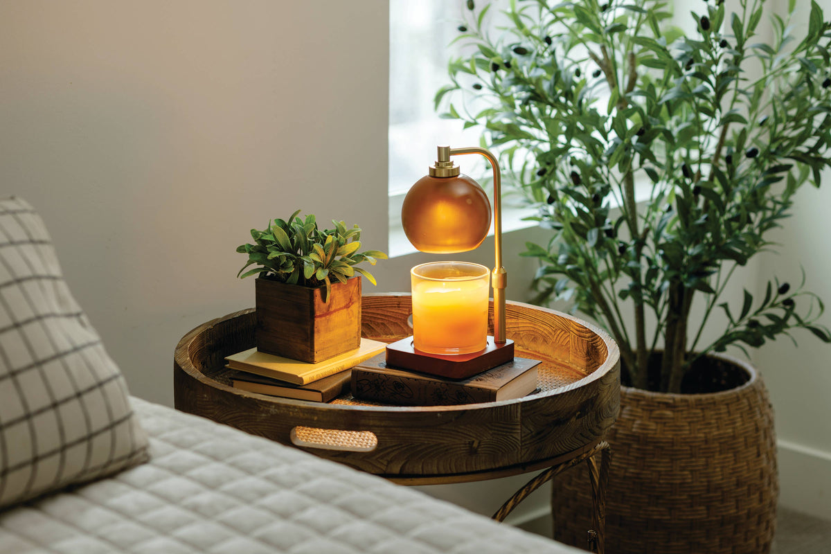 Amber glass candle warmer lamp styled with a scented candle on a living room console.