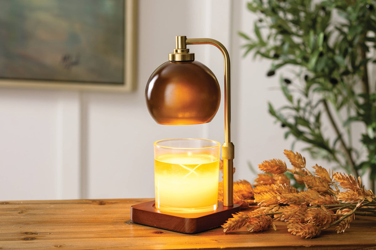 Amber glass candle warmer lamp styled with a scented candle on a living room console.