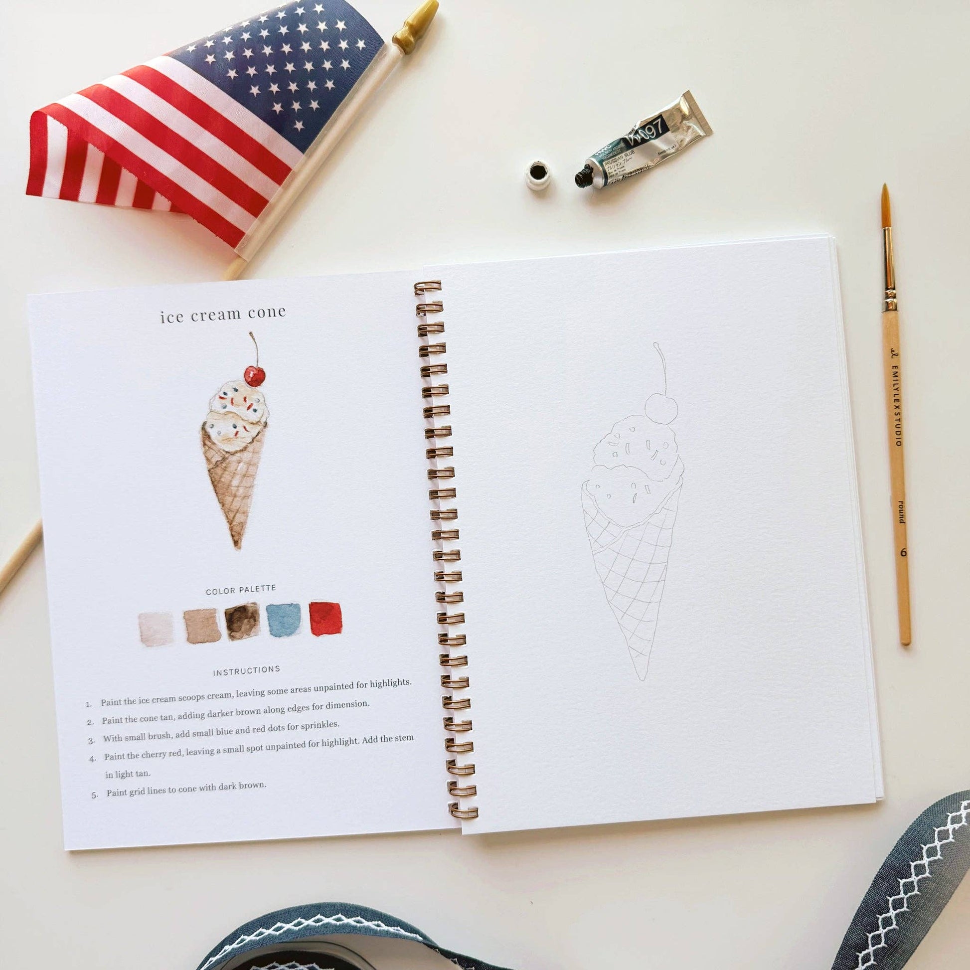 Americana watercolor workbook styled with paint supplies for a creative summer afternoon.