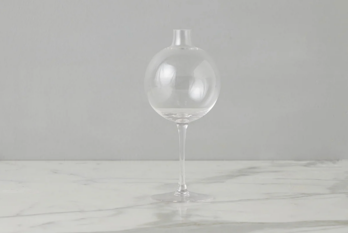 Clear glass vase on a marble surface with a gray background