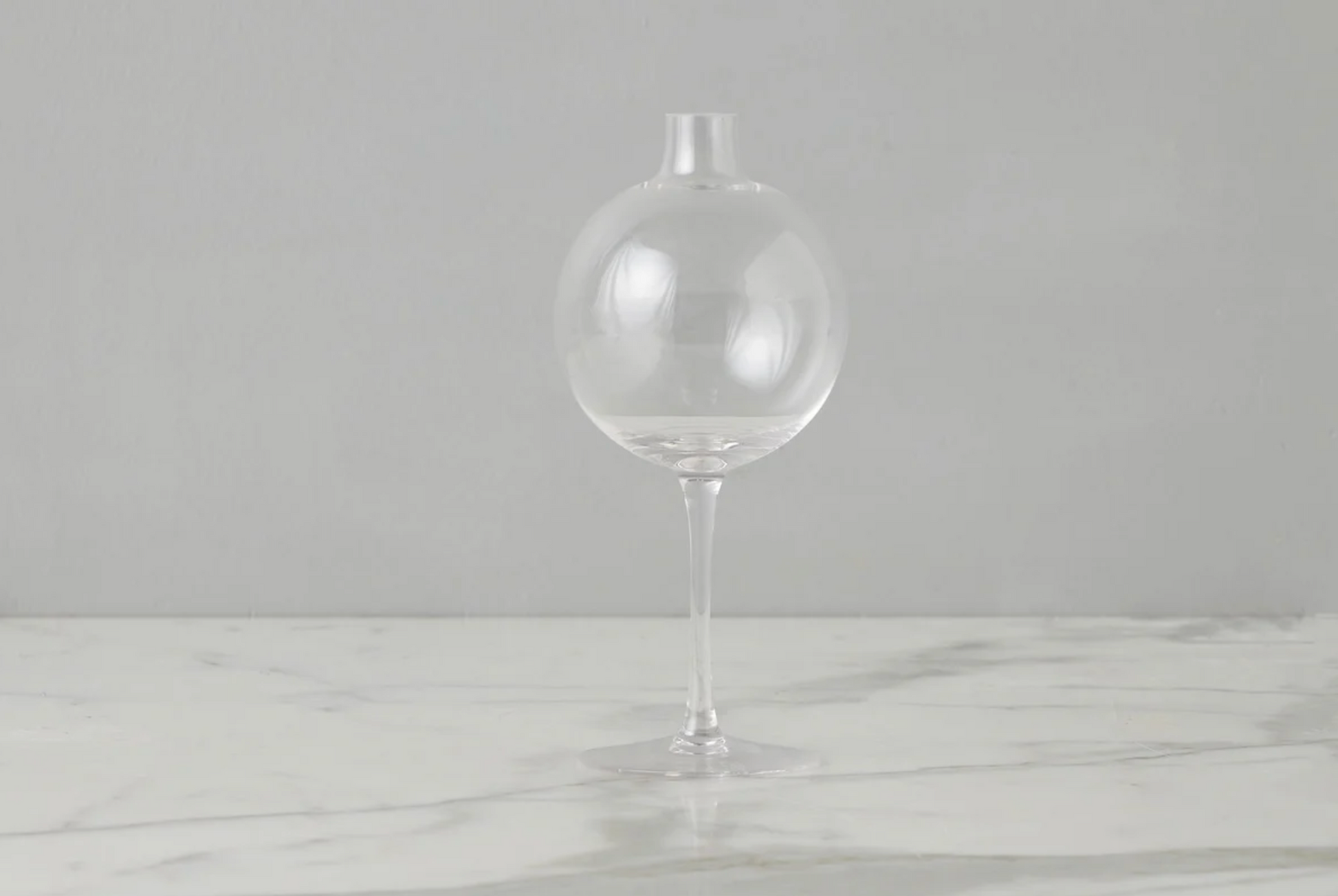 Clear glass vase on a marble surface with a gray background