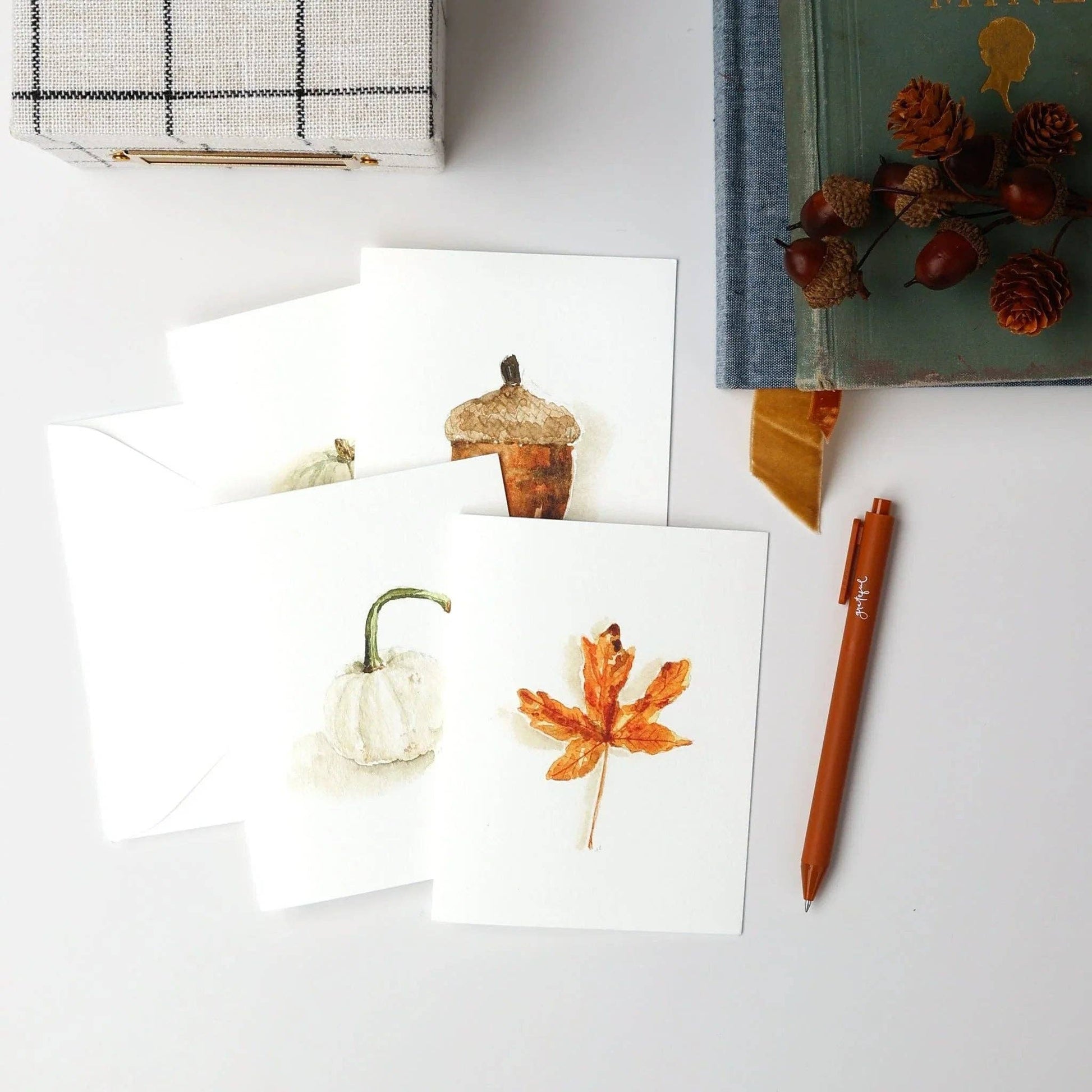 Autumn Watercolor Notecard Set by Emily Lex featuring watercolor illustrations of a maple leaf, acorn, white pumpkin, and green pumpkin with coordinating envelopes.