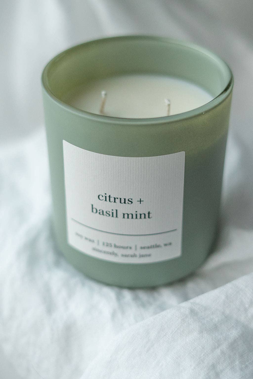 Botanist soy candle featuring a fresh citrus, basil, and mint fragrance in a sage green vessel.