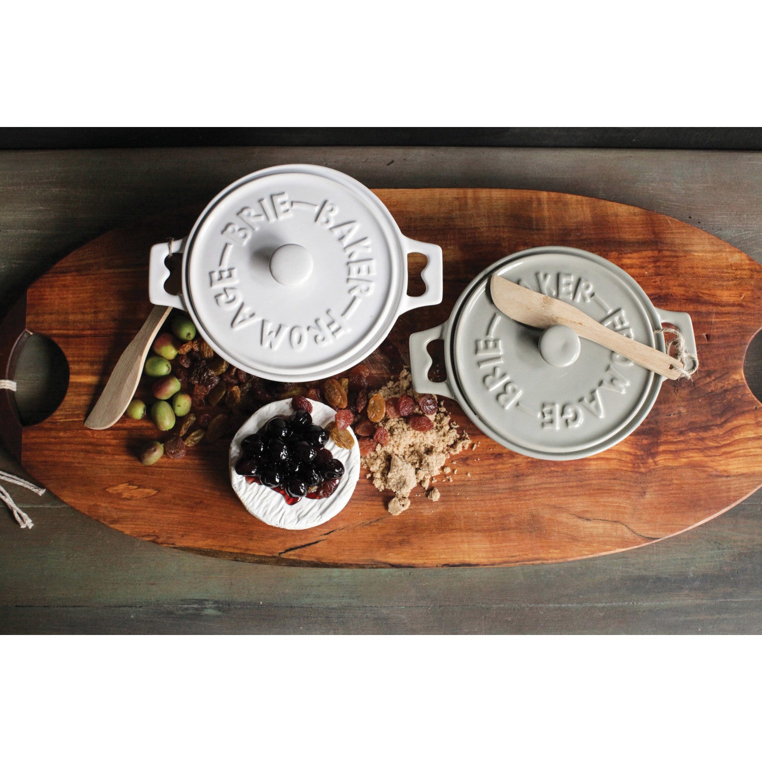 Warm baked brie served in a stoneware baker with honey, nuts, and charcuterie accompaniments.