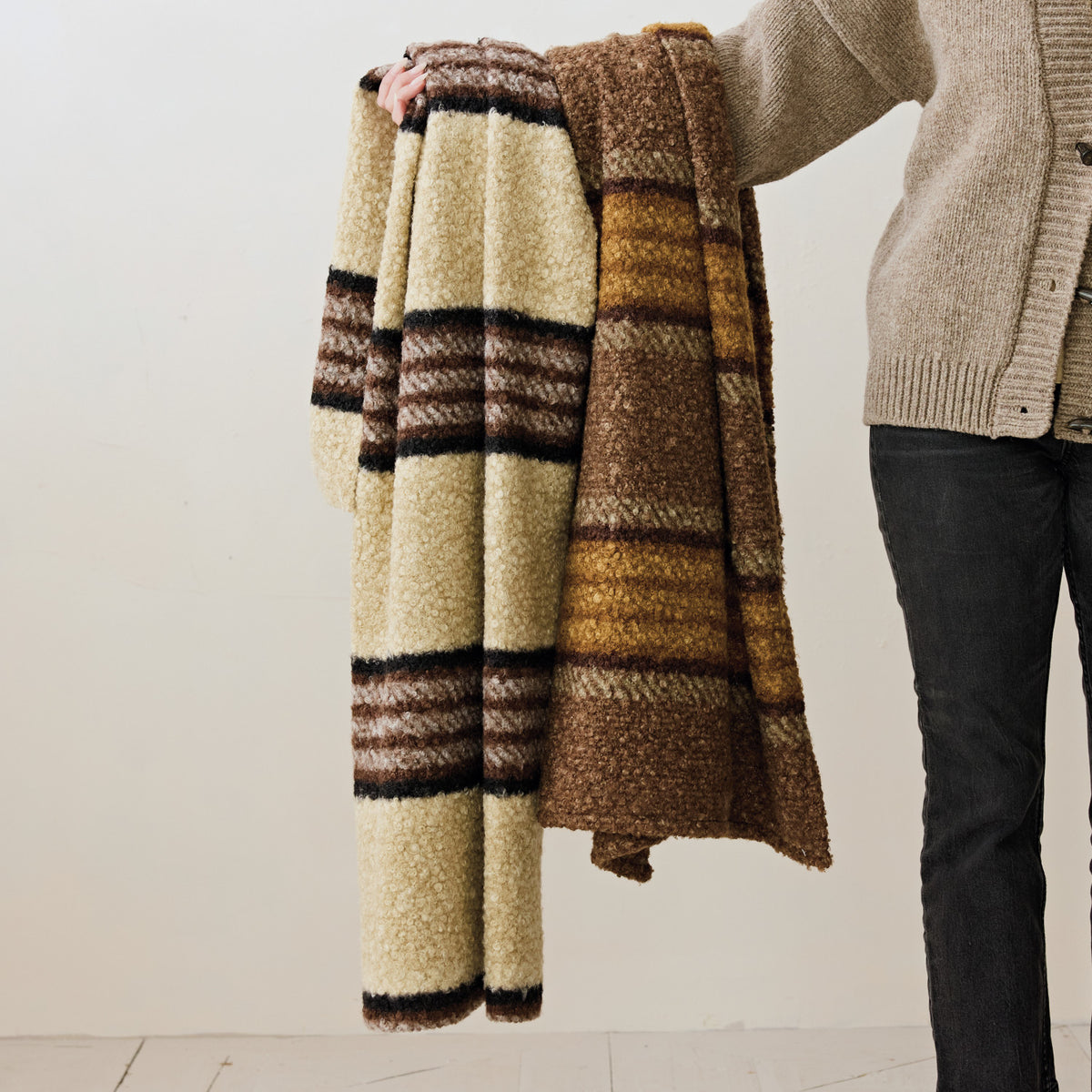 Faux sherpa striped throw blanket in warm brown, golden ochre, and black with a plush boucle-like texture.