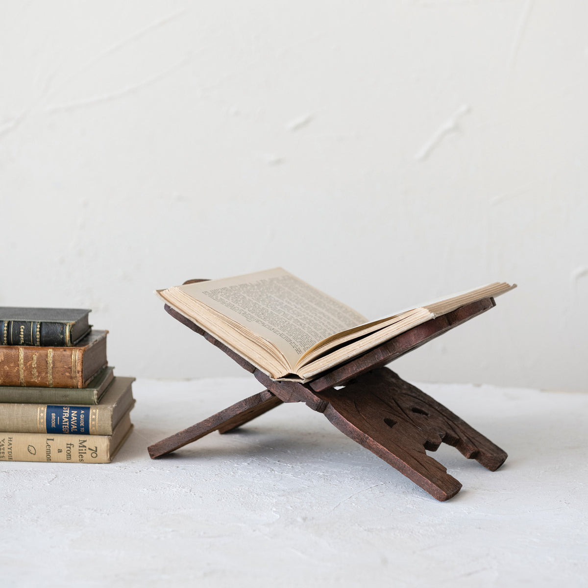 Front view of a carved reclaimed wood folding book stand with a warm walnut finish and pierced botanical motif.