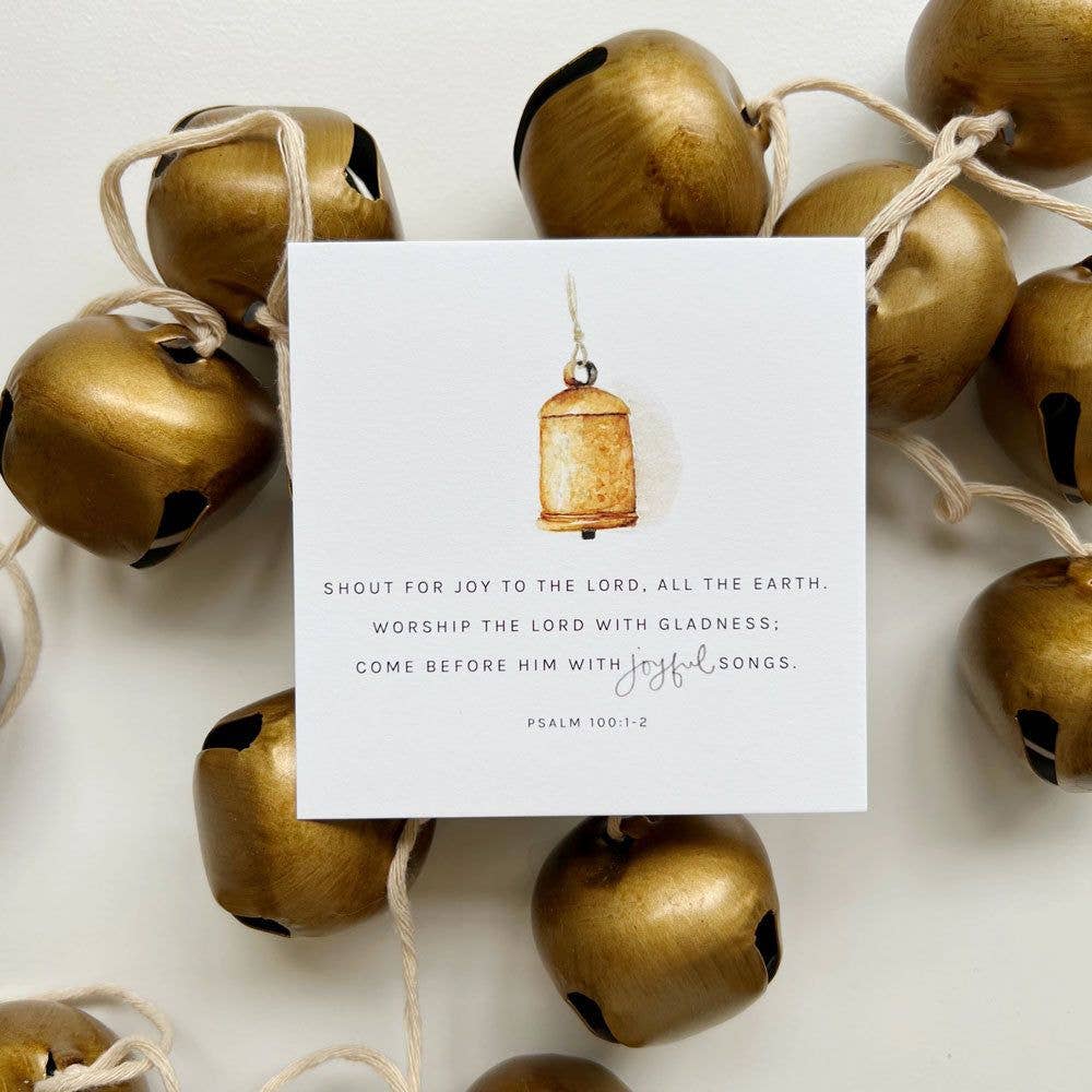 Gold bells with a white card featuring a Bible verse on a light background