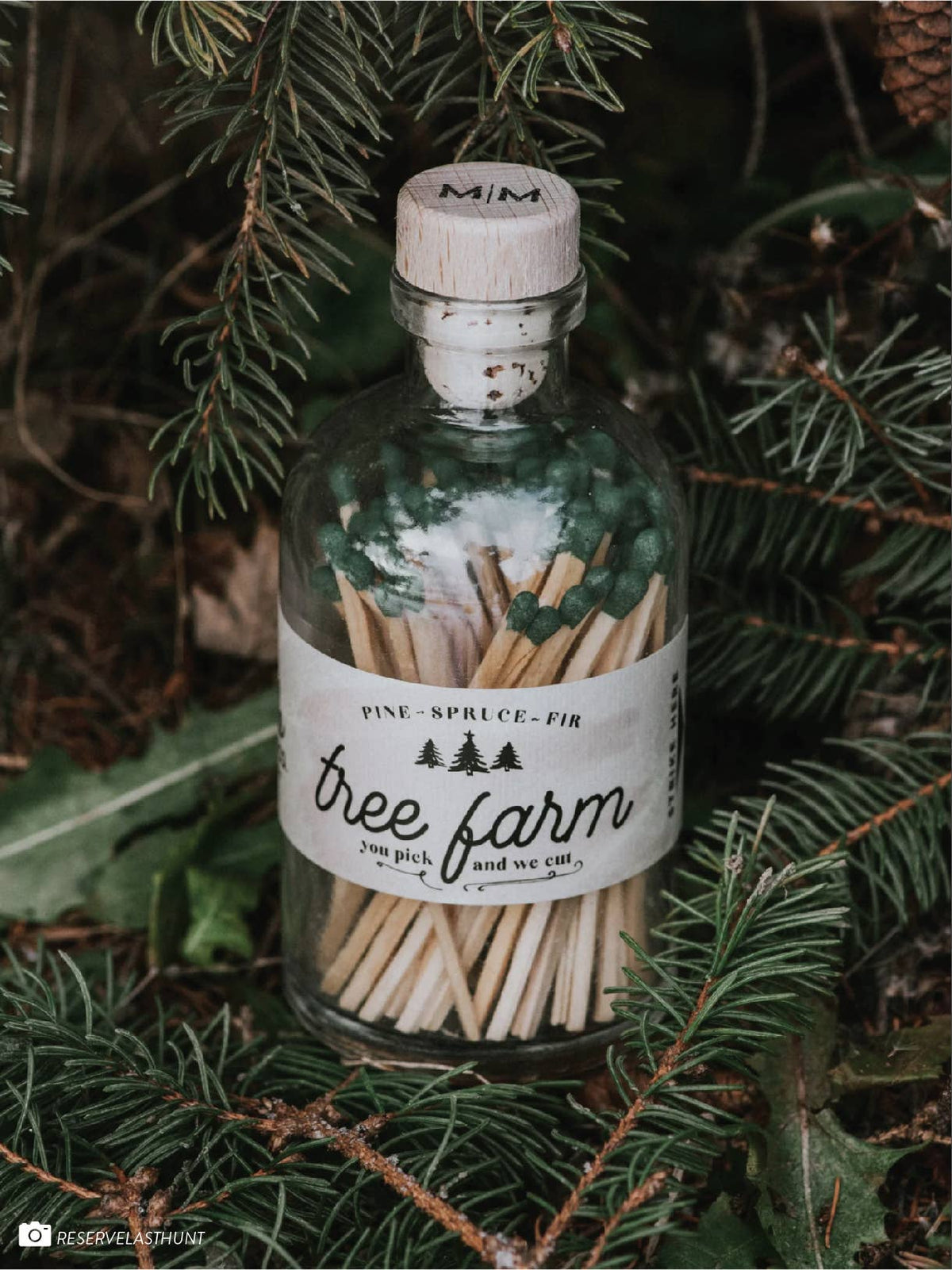 Christmas Tree Farm apothecary matches styled beside a seasonal candle and holiday greenery.