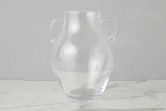 Clear glass vase with handles on a light gray background