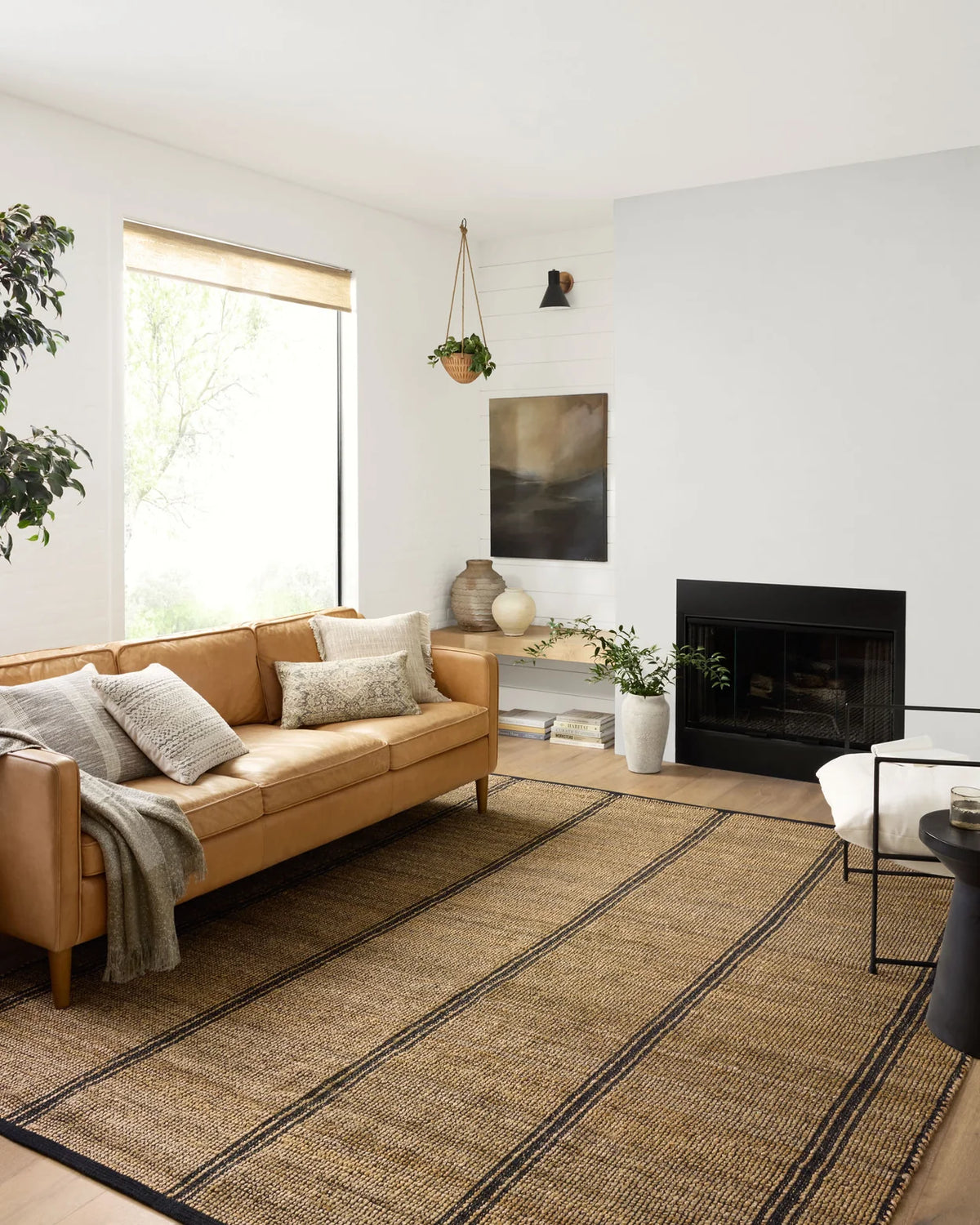 Colton Natural and Black area rug styled in an organic modern living room with oak furniture, linen upholstery, and layered natural textures.