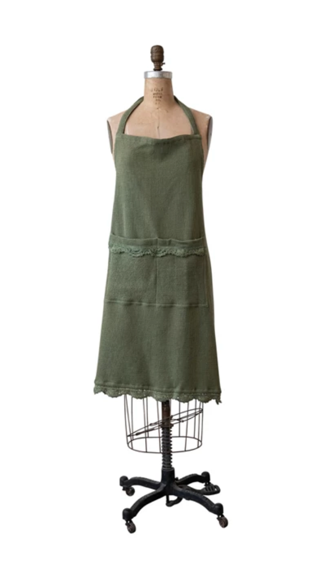 Green cotton waffle weave apron with crochet lace trim and functional front pockets.