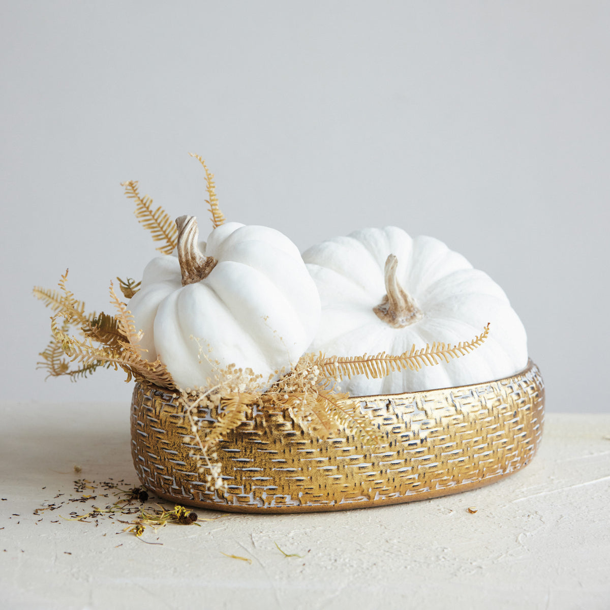 Cream resin pumpkin styled with collected neutral décor for a warm autumn display.
