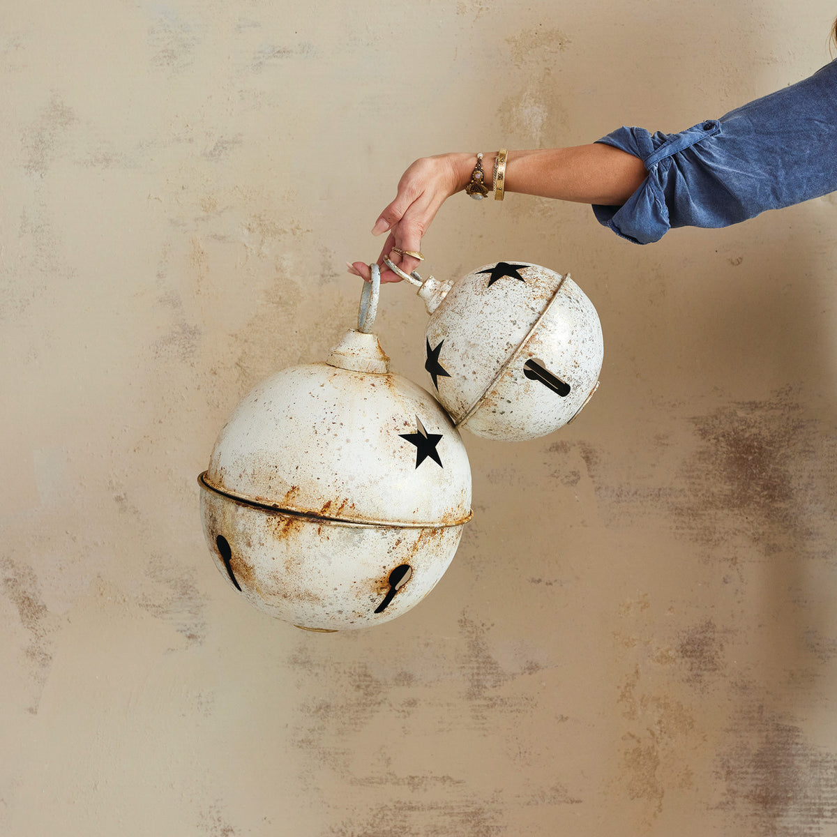 Distressed white metal Christmas bells in small and large sizes with decorative star-shaped cutouts.