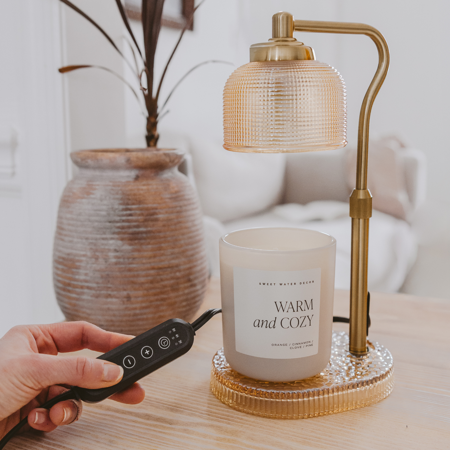 Close-up of the adjustable gold arm and glass shade of the electric candle warmer lamp.