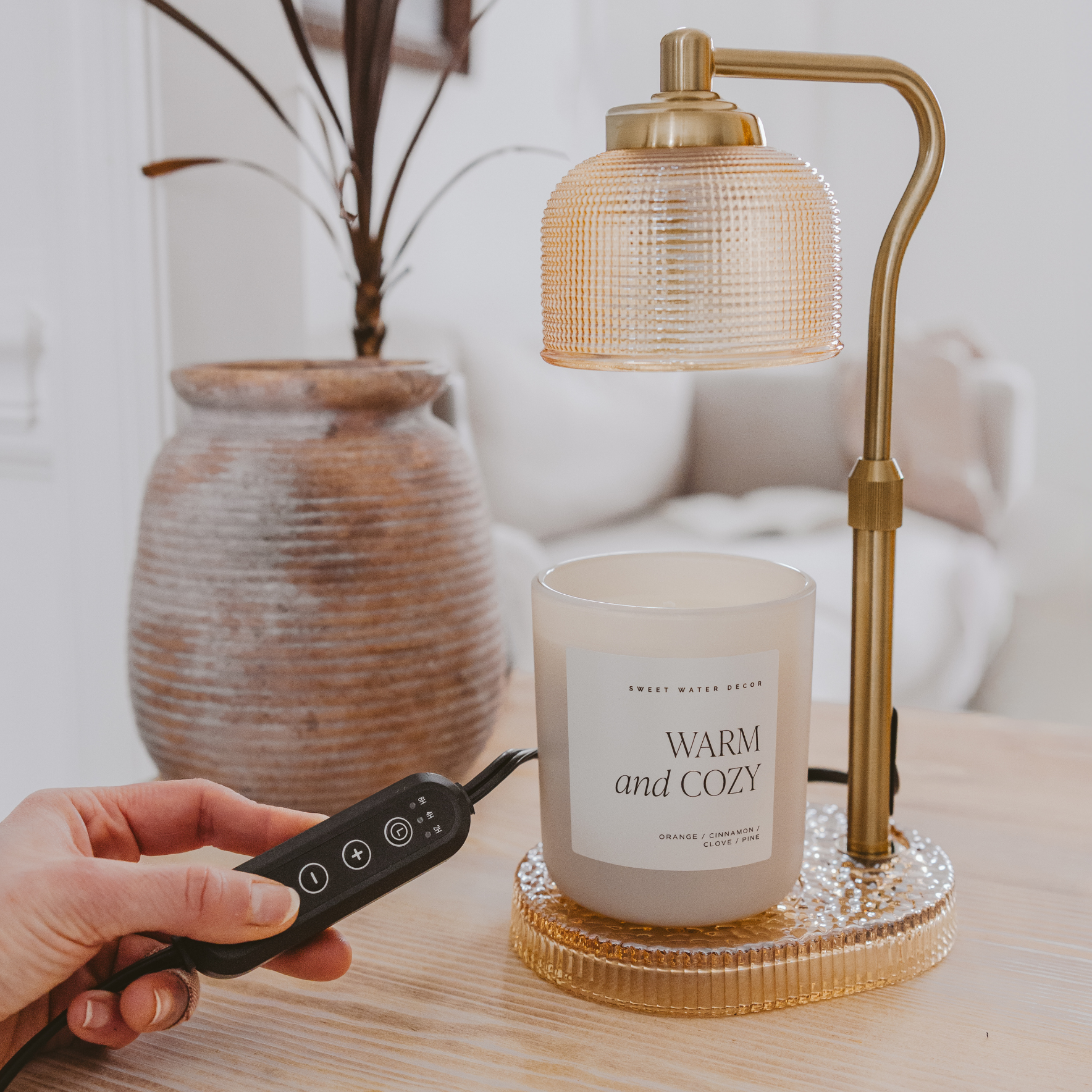 Close-up of the adjustable gold arm and glass shade of the electric candle warmer lamp.