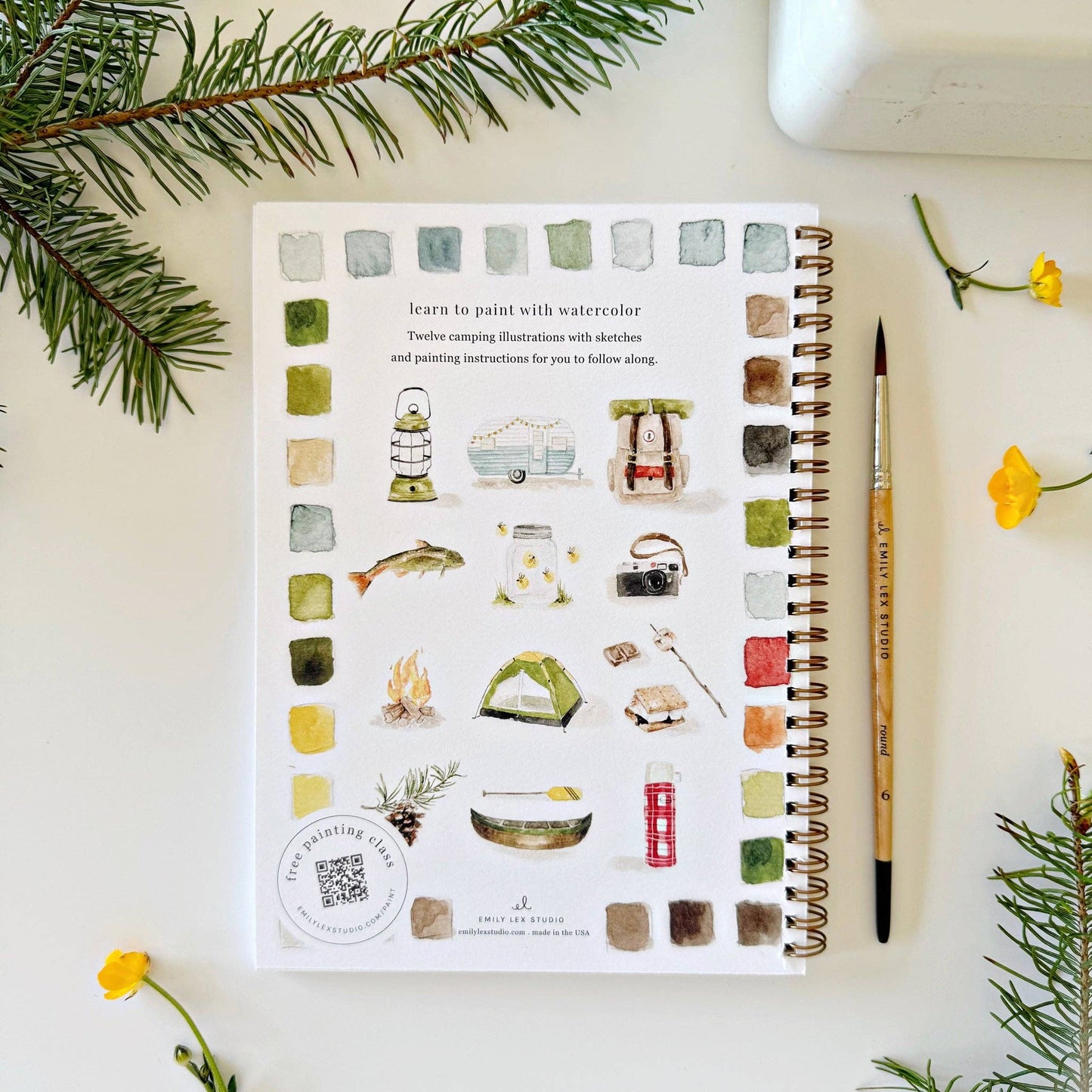 Spiral-bound watercolor workbook with lightly sketched camping-themed artwork.