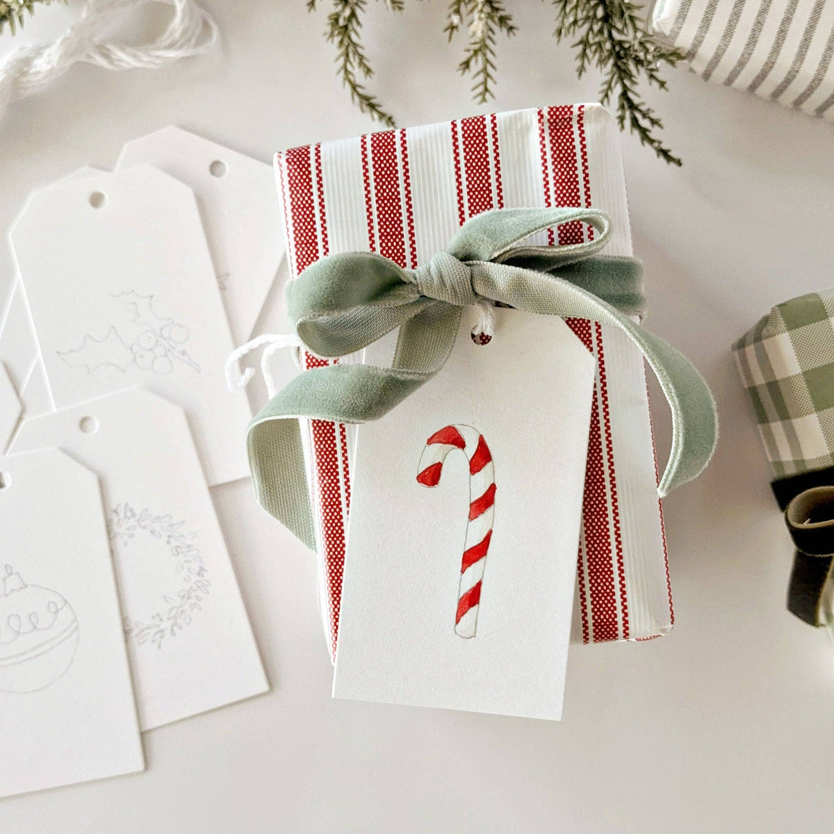 Close-up of an Emily Lex Christmas gift tag showing the outlined illustration on watercolor paper.