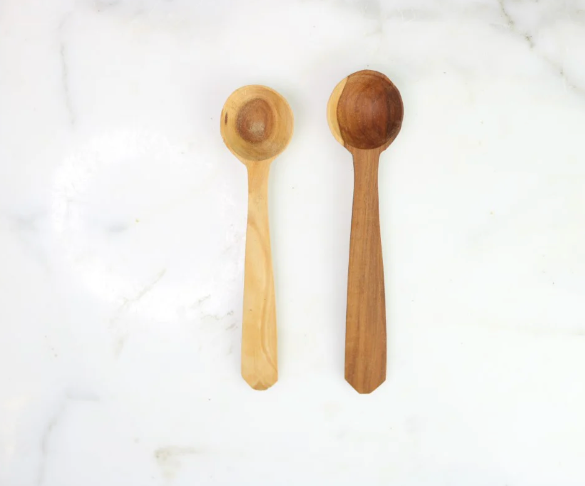 Two wooden spoons, one light wood and one dark wood, on a white background