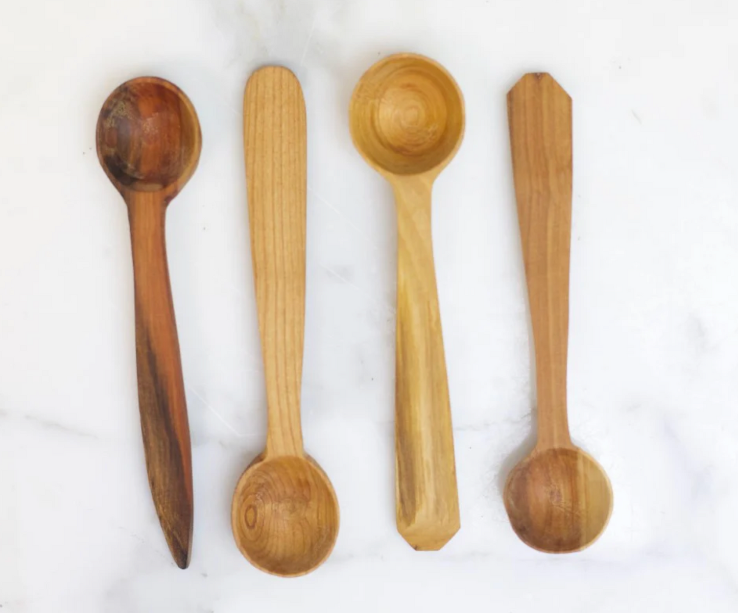 Four wooden spoons of different designs on a white background