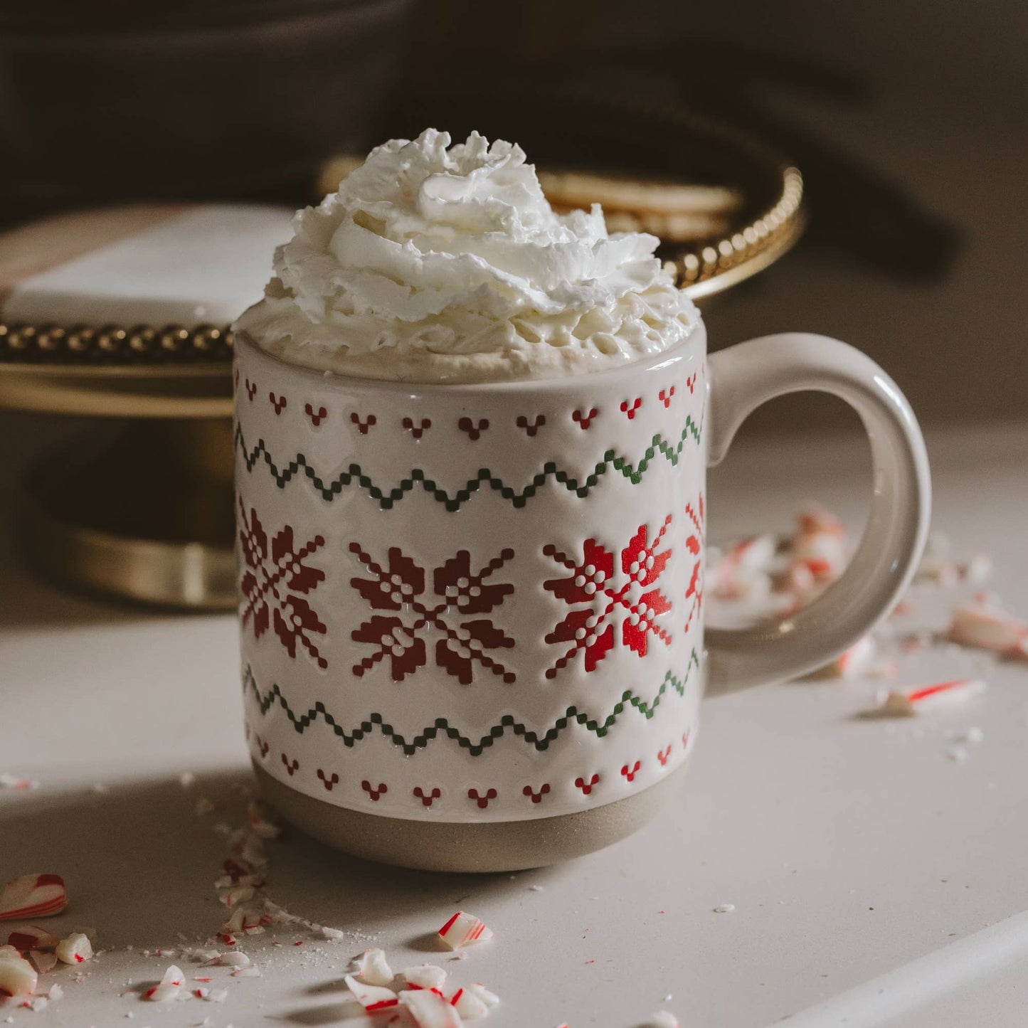 Cream stoneware coffee mug with an embossed red and green Fair Isle sweater pattern wrapping around the mug.