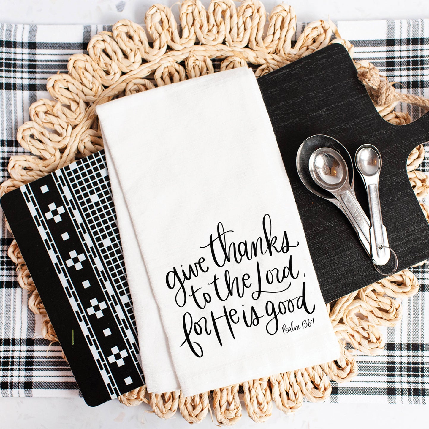 Faith-inspired tea towel draped over an oven handle in a warm farmhouse kitchen with wood cutting boards, pottery, and greenery.