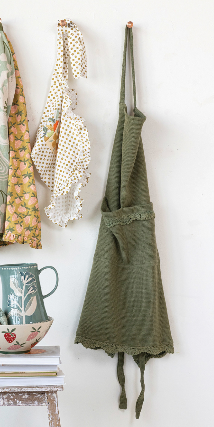 Soft green cotton apron with vintage-inspired details displayed in a French country kitchen.