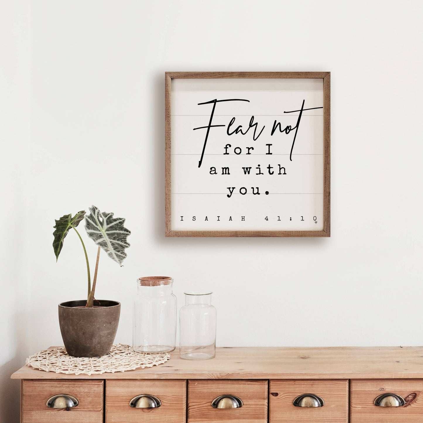 Fear Not scripture wall art hanging on a wall with natural wood furniture, plan, and glass decor.