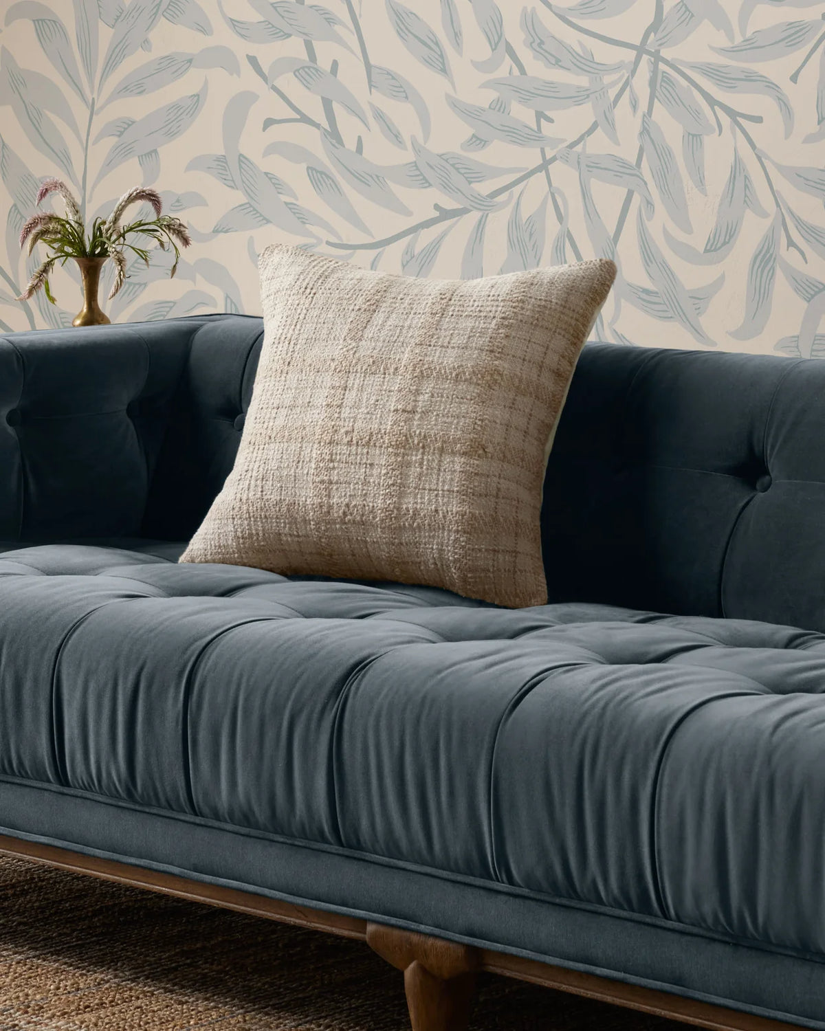 Fern ivory and beige check pillow styled on a blue velvet sofa with wood accents, greenery and natural textiles.