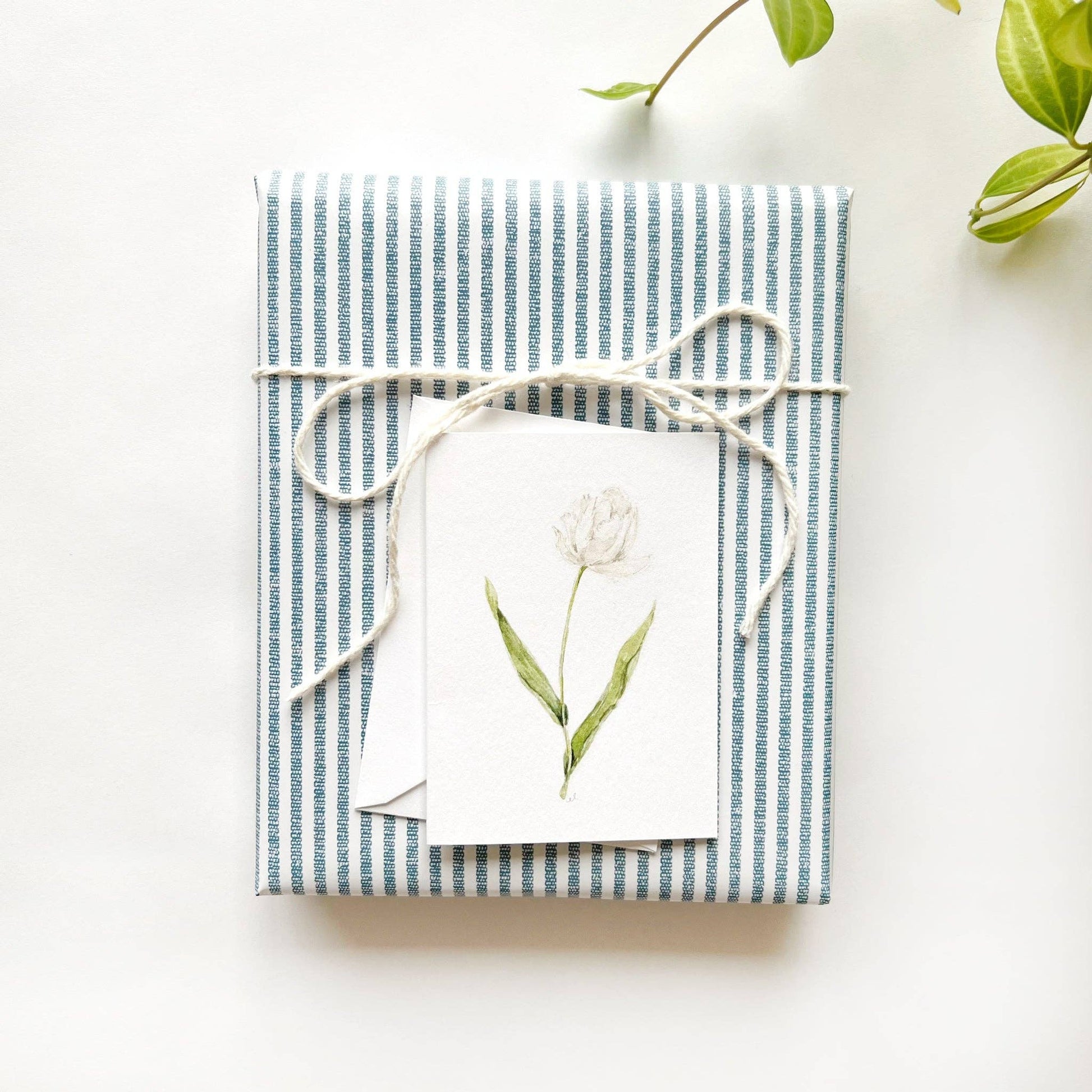 Botanical mini enclosure card attached to a wrapped gift.