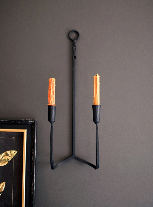 Forged iron double taper wall sconce designed to hold two taper candles.
