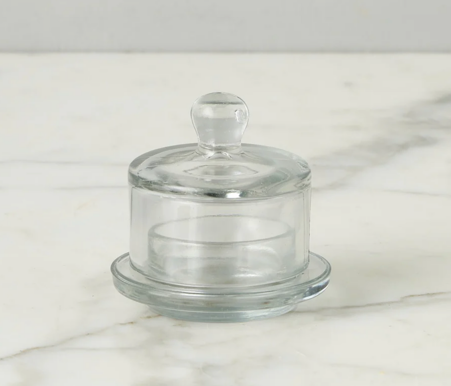 Clear glass jam jar stand with lid on a marble surface