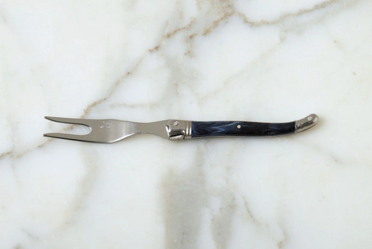 Fork with a dark handle on a marble surface