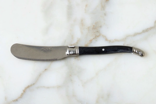 Butter knife with black handle on a marble surface