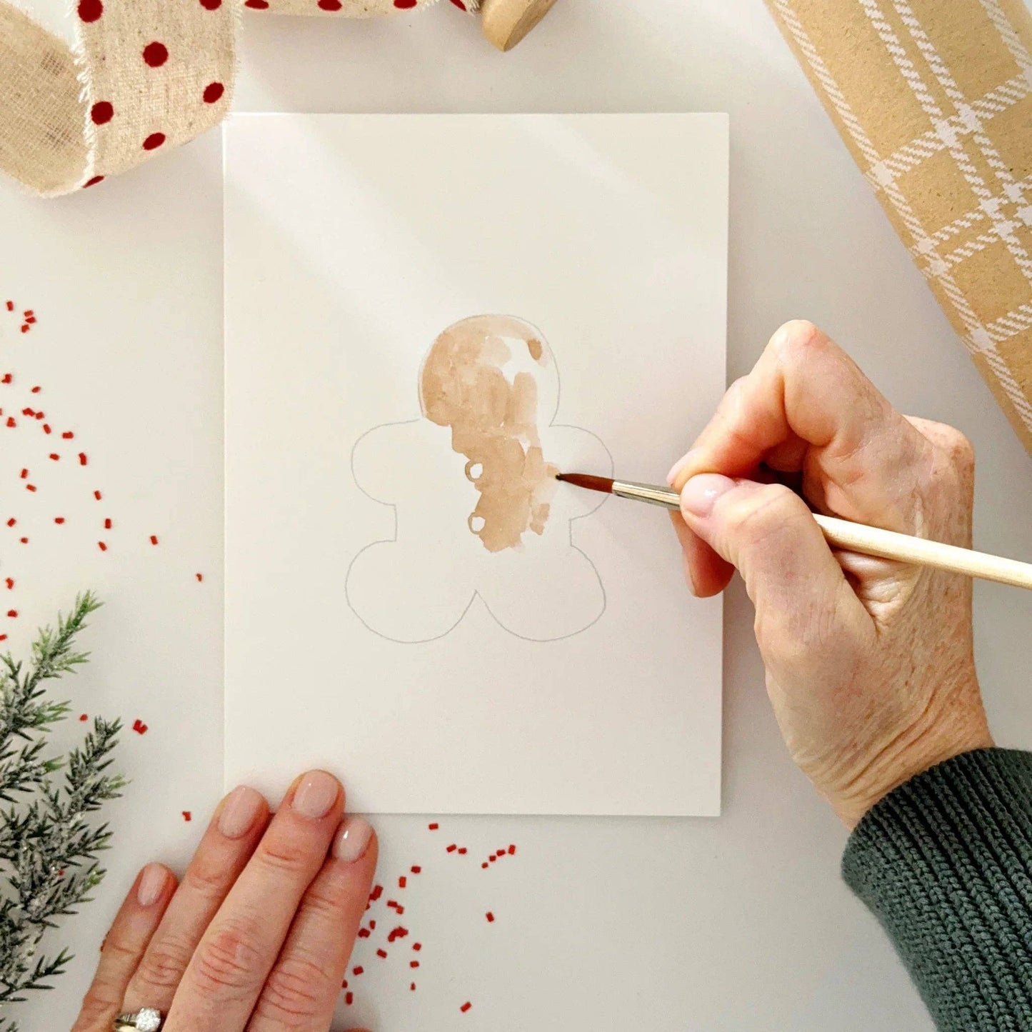 Close-up of watercolor-ready Christmas notecards featuring festive gingerbread and holiday illustrations printed on premium watercolor paper.