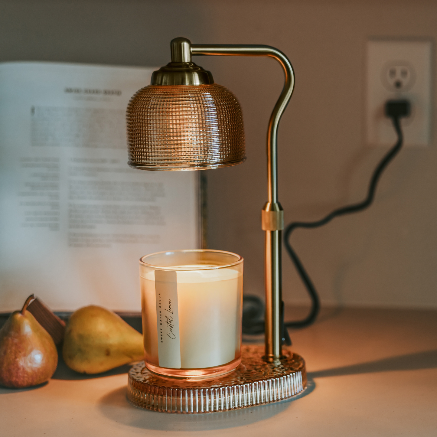Glass candle lamp warmer with a neutral glass shade, gold adjustable arm, and elegant flameless design.