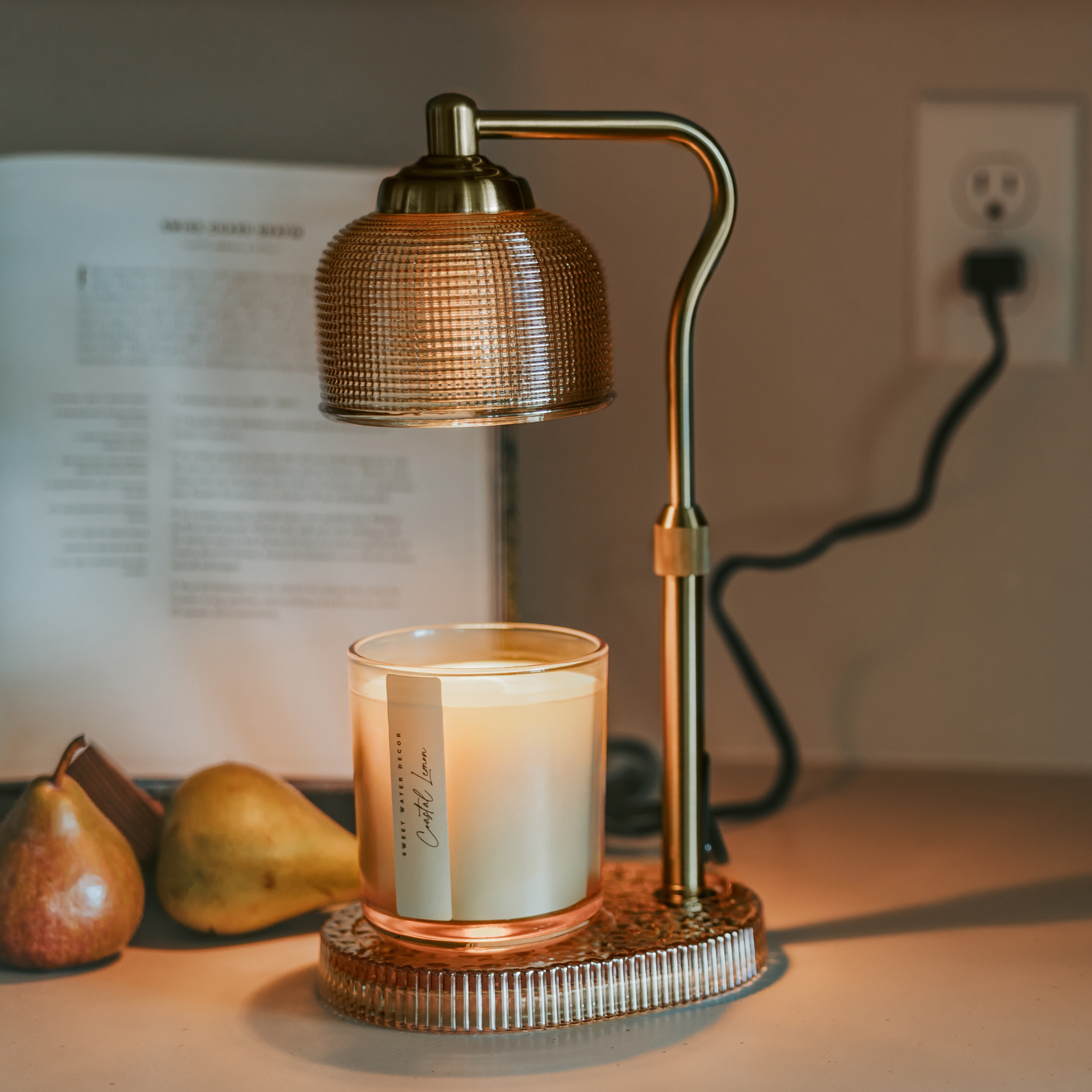 Glass candle lamp warmer with a neutral glass shade, gold adjustable arm, and elegant flameless design.