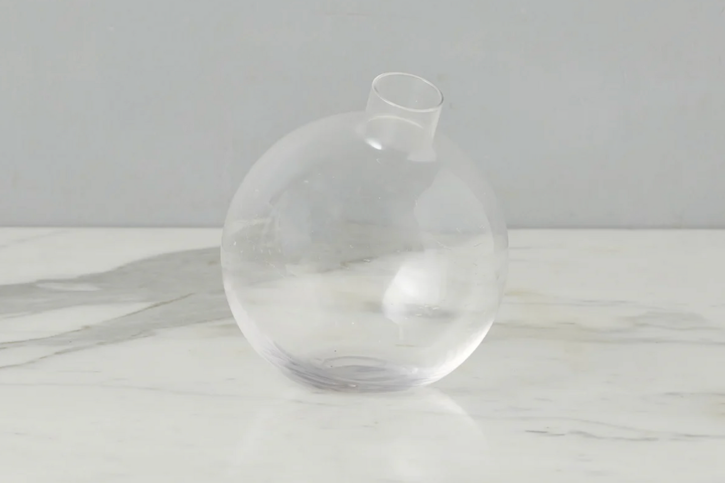 Clear glass vase on a white surface with a light gray background